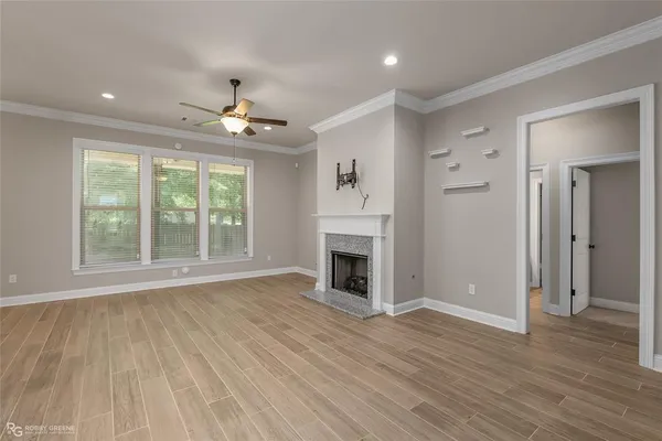 an empty room with wooden floor fireplace and windows