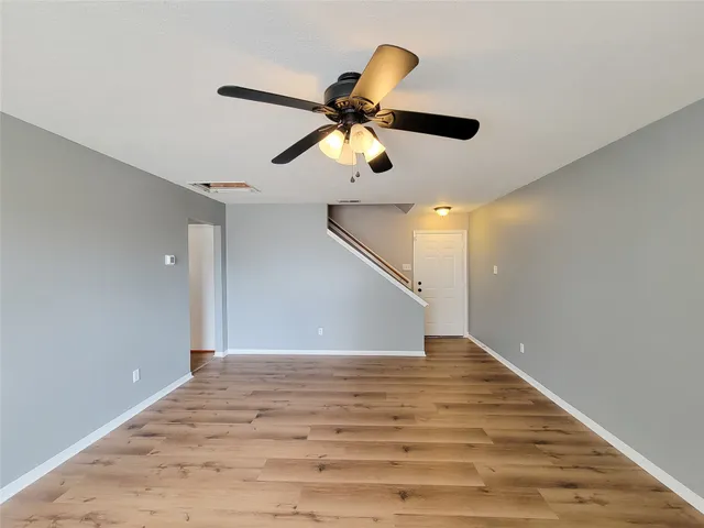 a view of a hallway with a chandelier fan and wooden floor