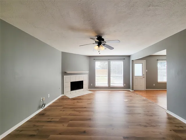 a view of an empty room with window and wooden floor