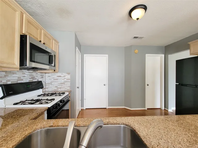 a kitchen with kitchen island granite countertop a sink stainless steel appliances and cabinets
