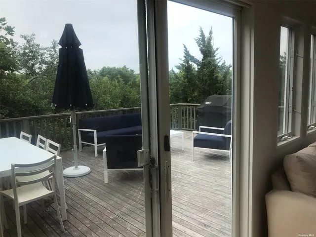a balcony with wooden floor table and chairs