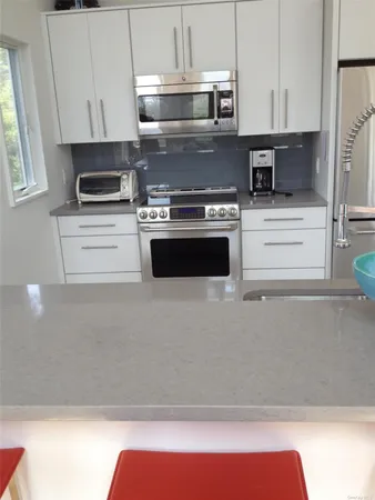 a kitchen with stainless steel appliances granite countertop a refrigerator a stove a sink a dining table and chairs