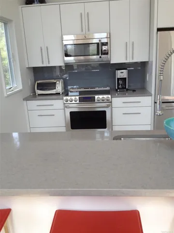 a kitchen with stainless steel appliances granite countertop a refrigerator a stove a sink a dining table and chairs