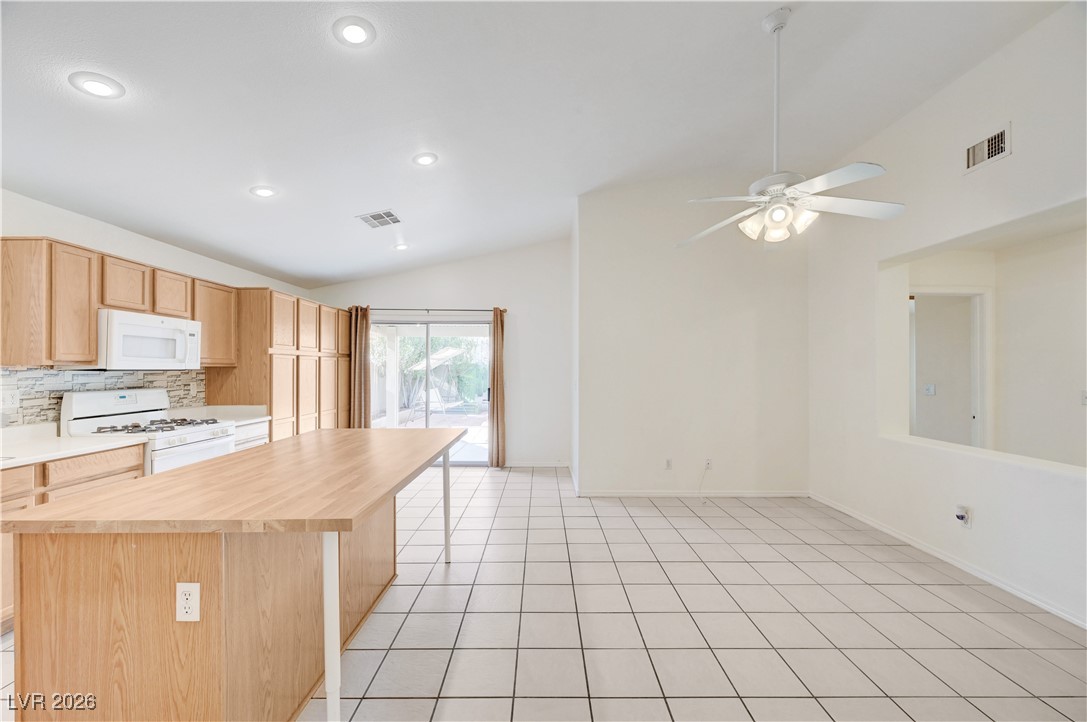 9929 Princess Cut Street Las Vegas, NV 89183 - Photo 11 of 52 Kitchen with vaulted ceiling, light brown cabinets, white appliances, a center island, and wooden counters