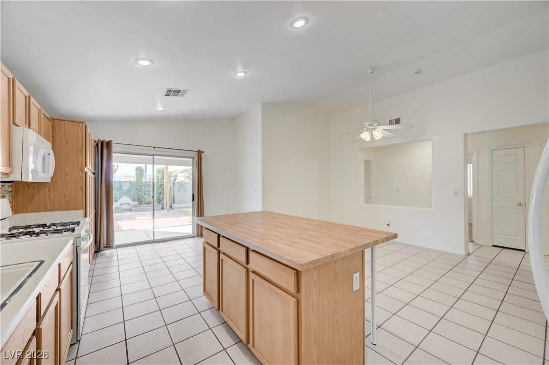 9929 Princess Cut Street Las Vegas, NV 89183 - Photo 24 of 52 Kitchen featuring light brown cabinets, vaulted ceiling, white appliances, a center island, and light tile patterned flooring