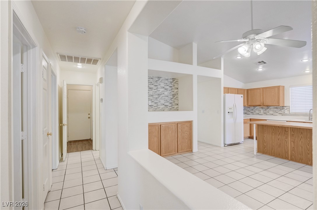 9929 Princess Cut Street Las Vegas, NV 89183 - Photo 34 of 52 Kitchen with vaulted ceiling, white refrigerator with ice dispenser, light tile patterned flooring, light countertops, and a ceiling fan