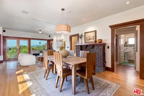 a kitchen with stainless steel appliances kitchen island granite countertop a stove a sink a refrigerator and a dining table with wooden floor