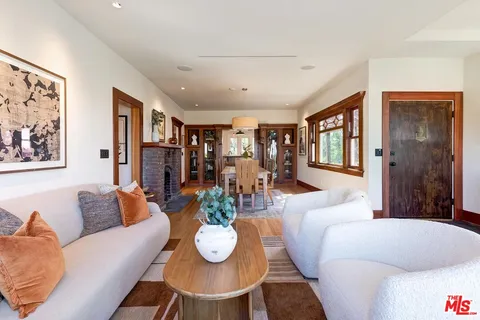 a living room with furniture potted plant and kitchen view