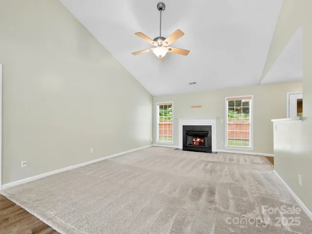 a view of a livingroom with a fireplace a ceiling fan and a fireplace