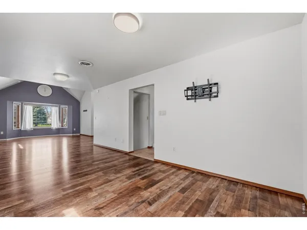 a view of an empty room with window and wooden floor