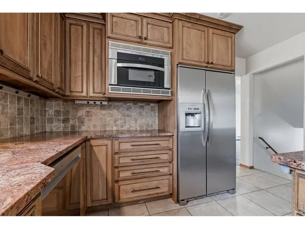 a kitchen with stainless steel appliances granite countertop a refrigerator a stove and a sink with wooden cabinets