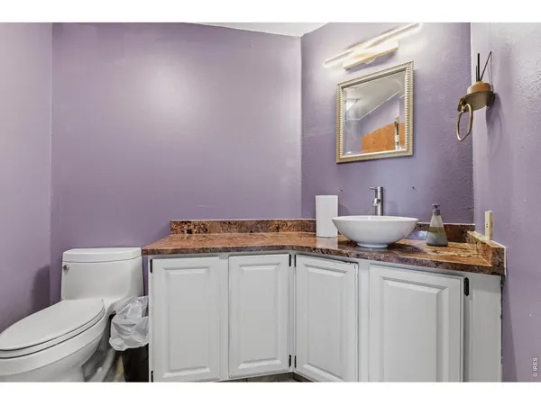 a bathroom with a granite countertop sink a toilet and mirror