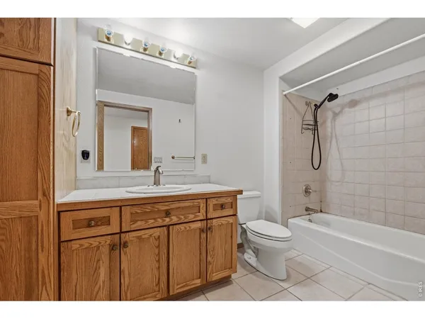 a bathroom with a granite countertop sink a toilet a mirror a bathtub and shower
