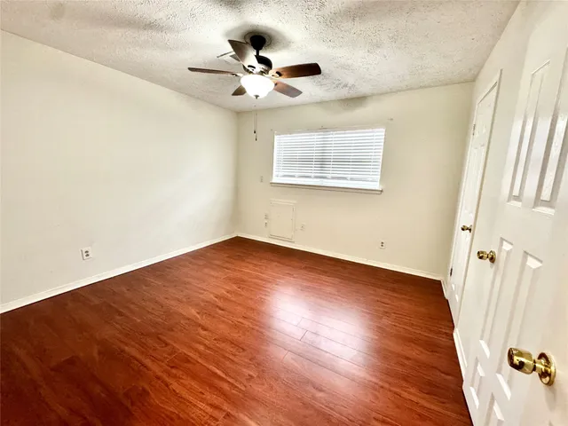 an empty room with wooden floor and fan