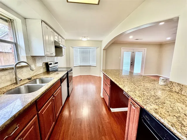 a kitchen with stainless steel appliances granite countertop wooden floors wooden cabinets and sink