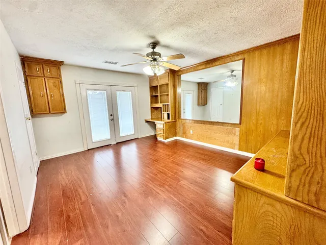 an empty room with wooden floor closet and windows