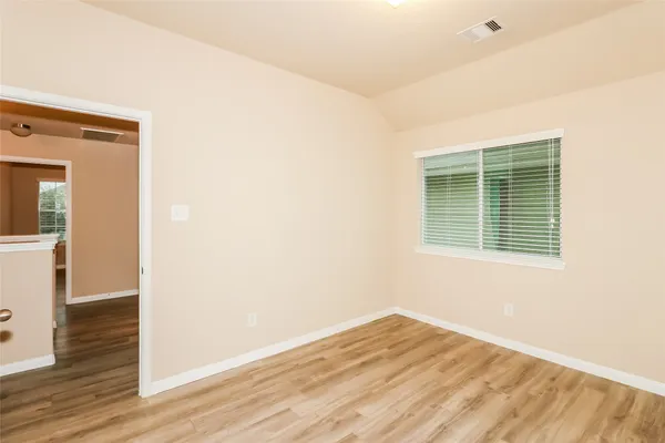 a view of empty room with wooden floor and fan
