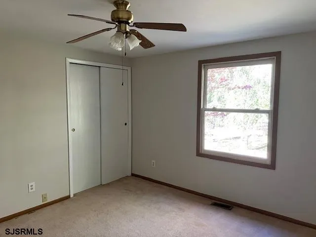 an empty room with a window and a fan