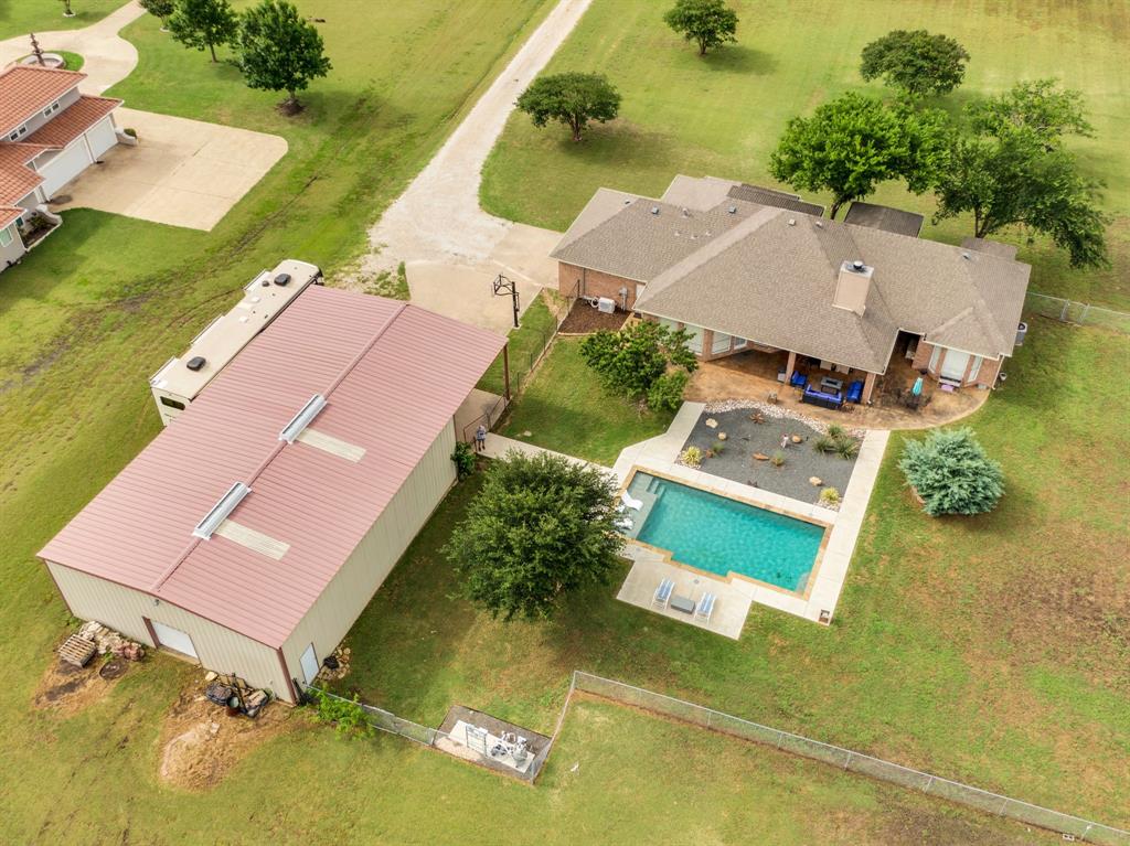 431 Mc Alpin Road Midlothian, TX 76065 - Photo 17 of 18 Expansive property featuring a rectangular swimming pool with concrete decking, a covered patio, a detached metal-sided outbuilding with a metal roof, and a gravel driveway