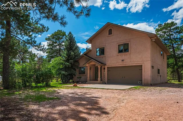 a front view of a house with a yard and trees