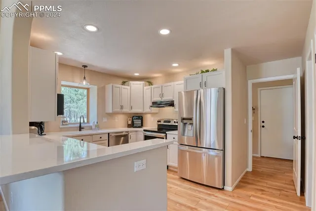 a kitchen with stainless steel appliances a refrigerator a sink a stove a microwave a center island and a window