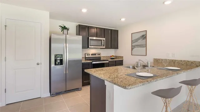 a kitchen with stainless steel appliances granite countertop a sink and a refrigerator