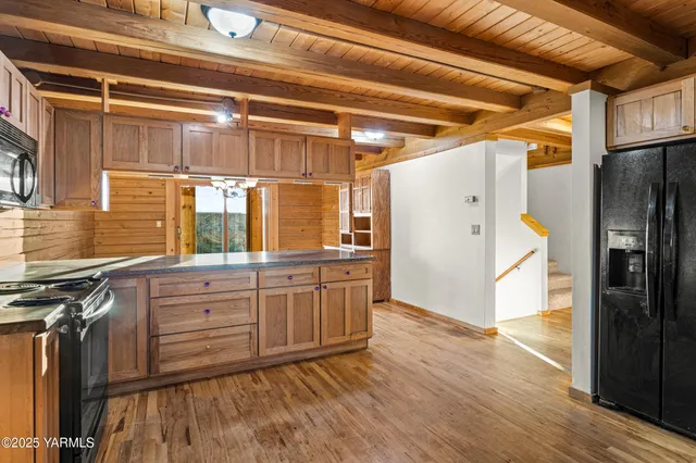 a kitchen with granite countertop a refrigerator a sink and wooden floors