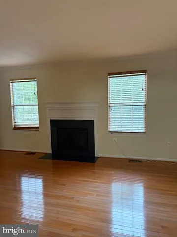an empty room with wooden floor fireplace and windows