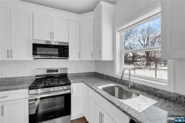 a kitchen with granite countertop a sink and a stove top oven