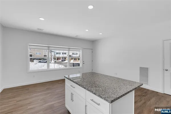 a kitchen with granite countertop white cabinets and a window