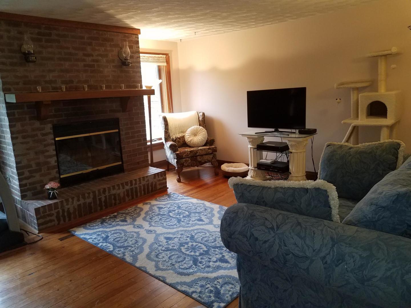 10481 Cherry Valley Road Genoa, IL 60135 - Photo 5 of 17 a living room with furniture a flat screen tv and a fireplace