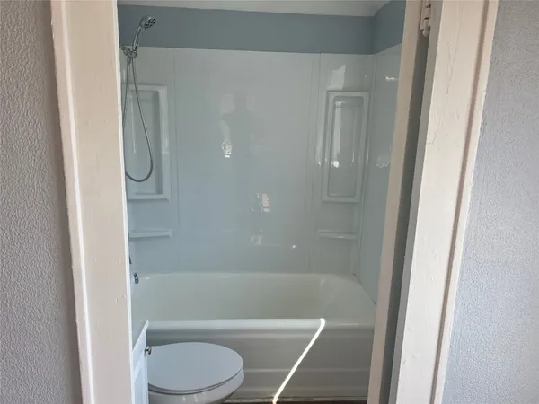 a bathroom with a granite countertop bathtub shower and toilet