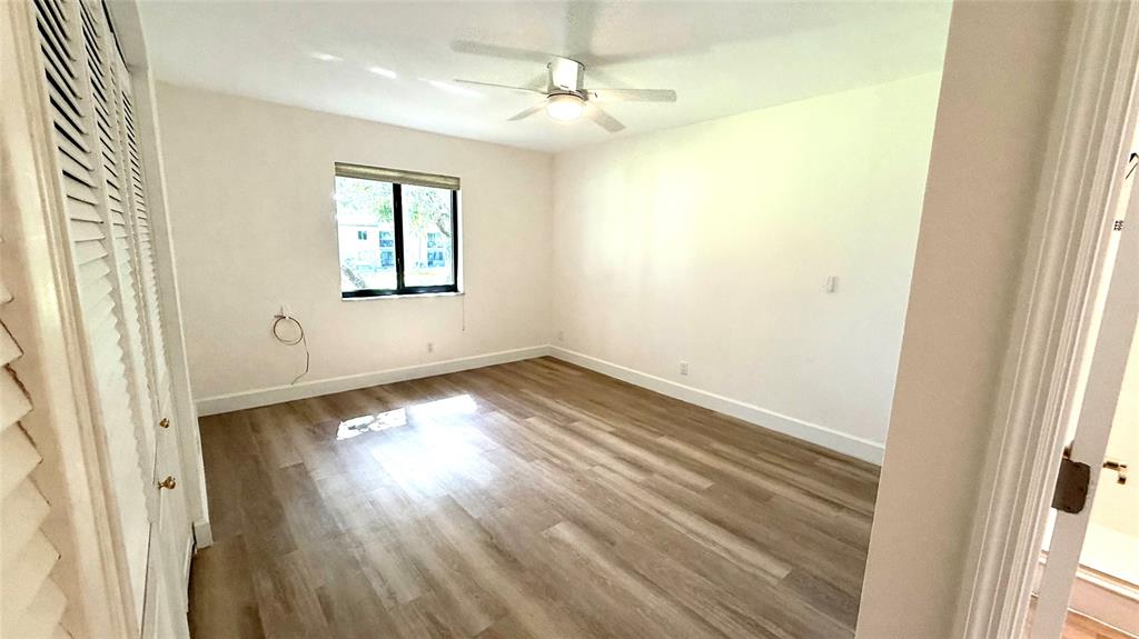 110 Northwest 70th Street, Unit 202 Boca Raton, FL 33487 - Photo 11 of 13 an empty room with wooden floor and windows