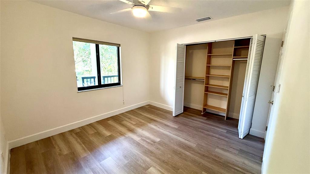 110 Northwest 70th Street, Unit 202 Boca Raton, FL 33487 - Photo 5 of 13 an empty room with wooden floor closet and windows