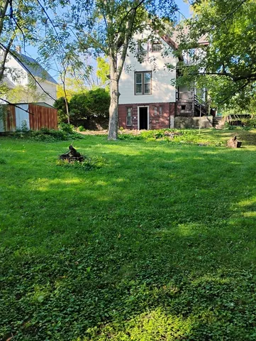 a view of a white house that has a tree in front of a house
