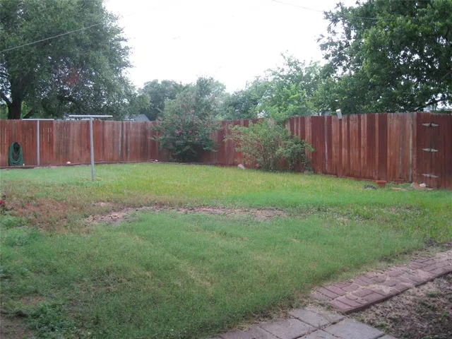 a view of a house with brick walls and a yard with plants