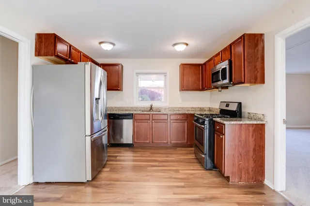 a kitchen with granite countertop a refrigerator stove top oven and sink