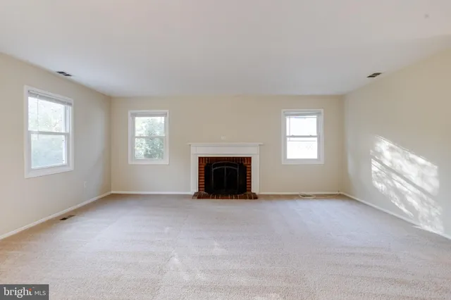 an empty room with windows and fireplace