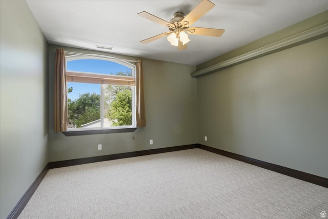12317 Cypress Point Way Draper, UT 84020 - Photo 22 of 41 Spacious room featuring a large arched window, ceiling fan with light kit, textured carpeting, crown molding, and dark baseboards