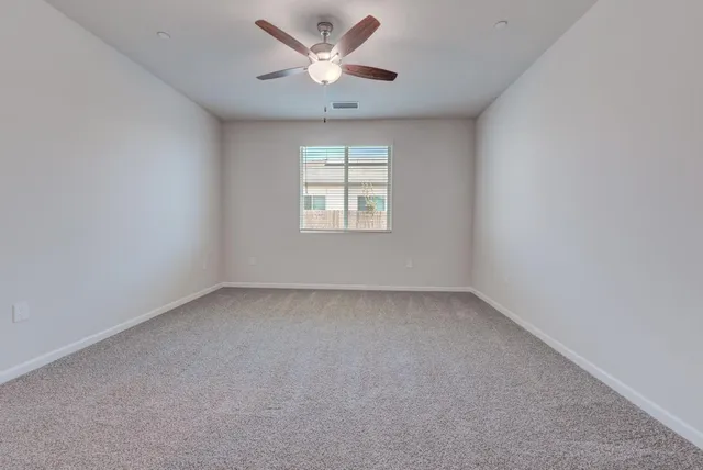 an empty room with a window and a fan