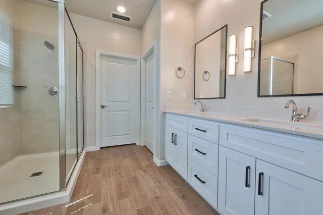 a spacious bathroom with a double vanity sink a mirror a shower and a bathtub