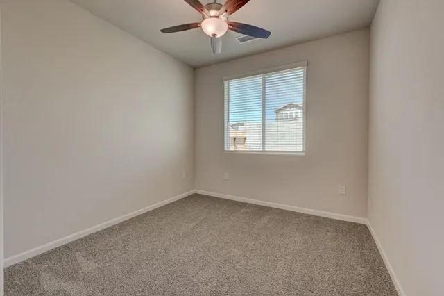 an empty room with a window and a fan