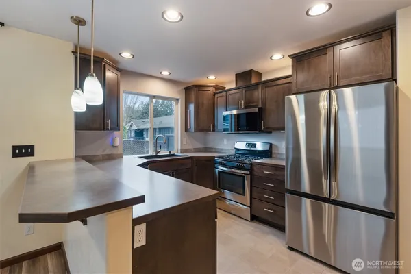 a kitchen with stainless steel appliances a refrigerator a sink a stove a microwave and island