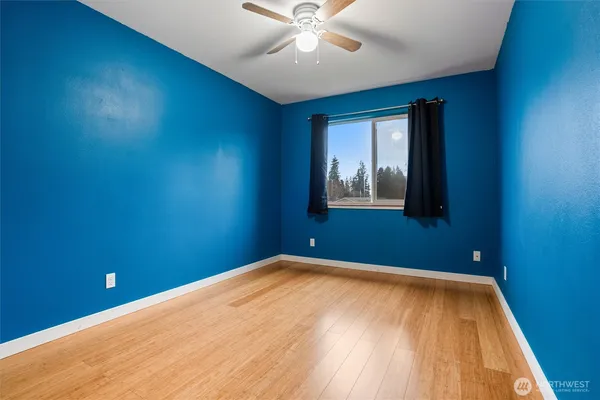 a view of an empty room with window and wooden floor