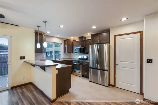 a kitchen with stainless steel appliances granite countertop a refrigerator a stove and a sink