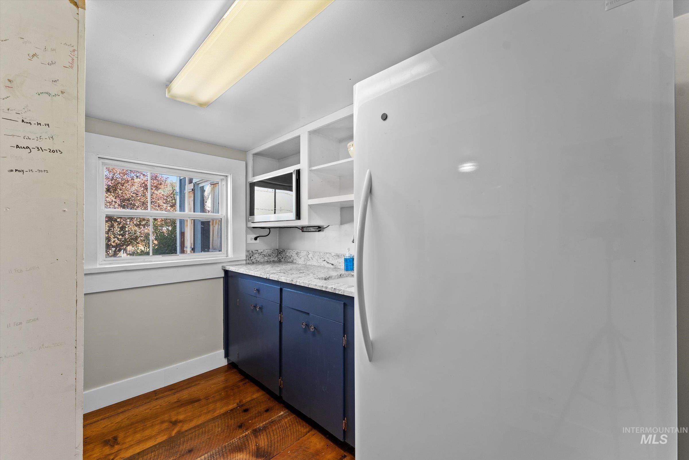 315 South Middlefork Road Garden Valley, ID 83622 - Photo 11 of 49 Kitchen with freestanding refrigerator, dark wood finished floors, open shelves, blue cabinetry, and light stone countertops
