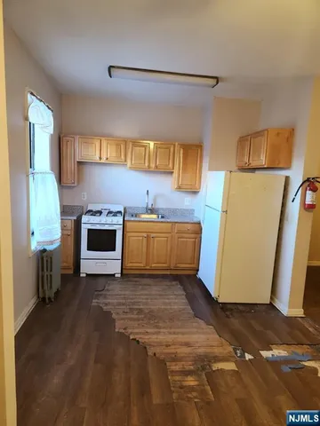 a kitchen with stainless steel appliances granite countertop a refrigerator a stove and a sink with wooden floor