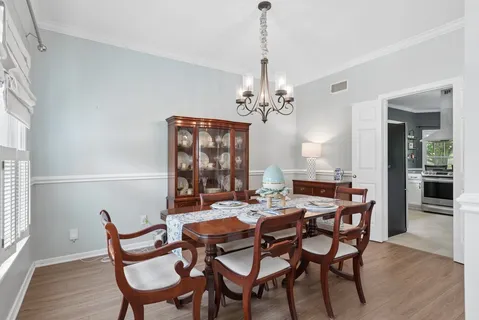 a view of a dining room and livingroom with furniture wooden floor a chandelier