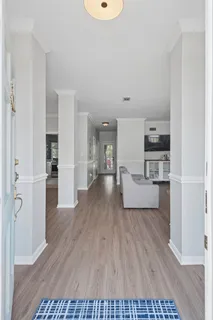 a living room with stainless steel appliances furniture a refrigerator and a wooden floor