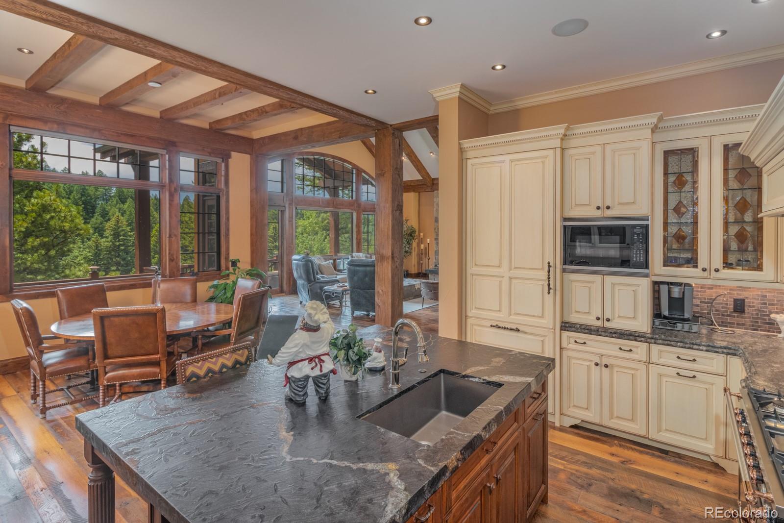 30 West Ranch Trail Morrison, CO 80465 - Photo 16 of 40 a kitchen with stainless steel appliances granite countertop a stove a kitchen island a table and chairs